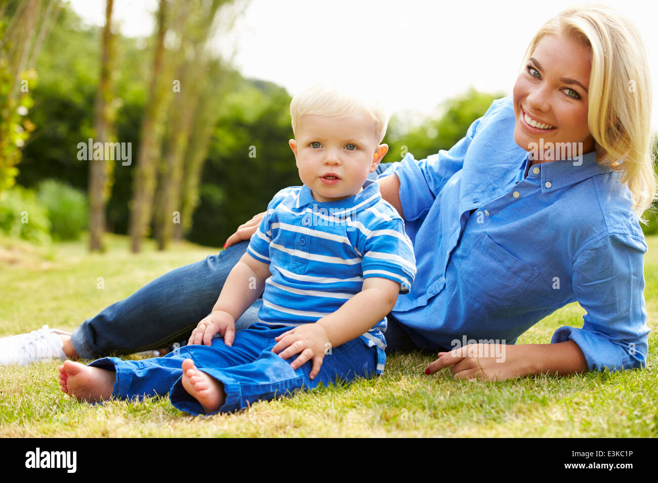 Madre e figlio giovane seduto in giardino insieme Foto Stock