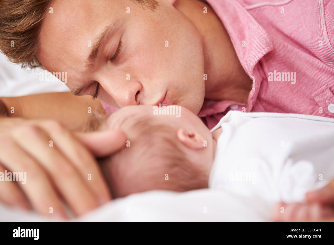 Padre baciare Bambina che giacciono nel letto insieme Foto Stock