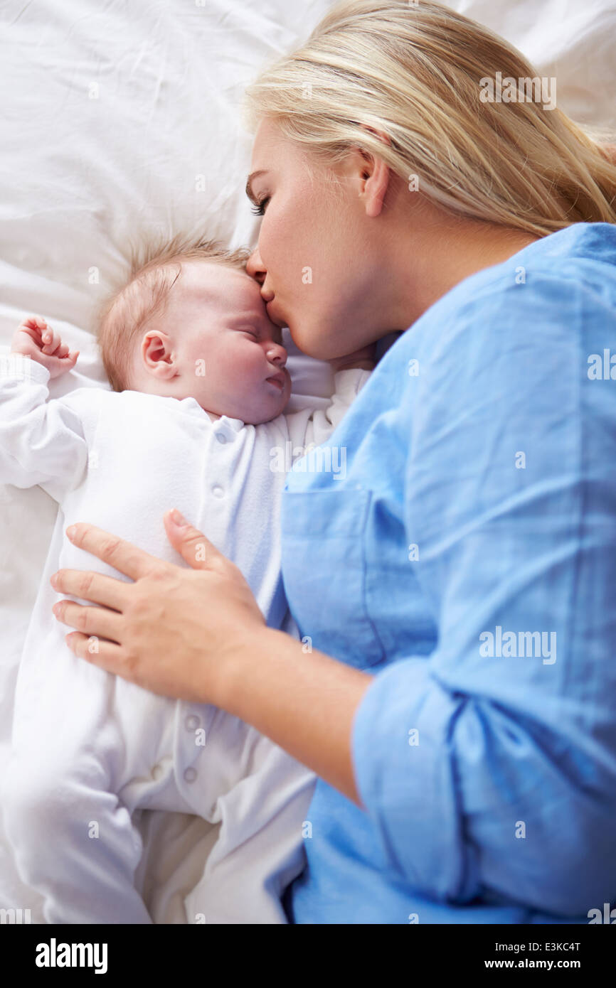 Madre baciare Bambina che giacciono nel letto insieme Foto Stock