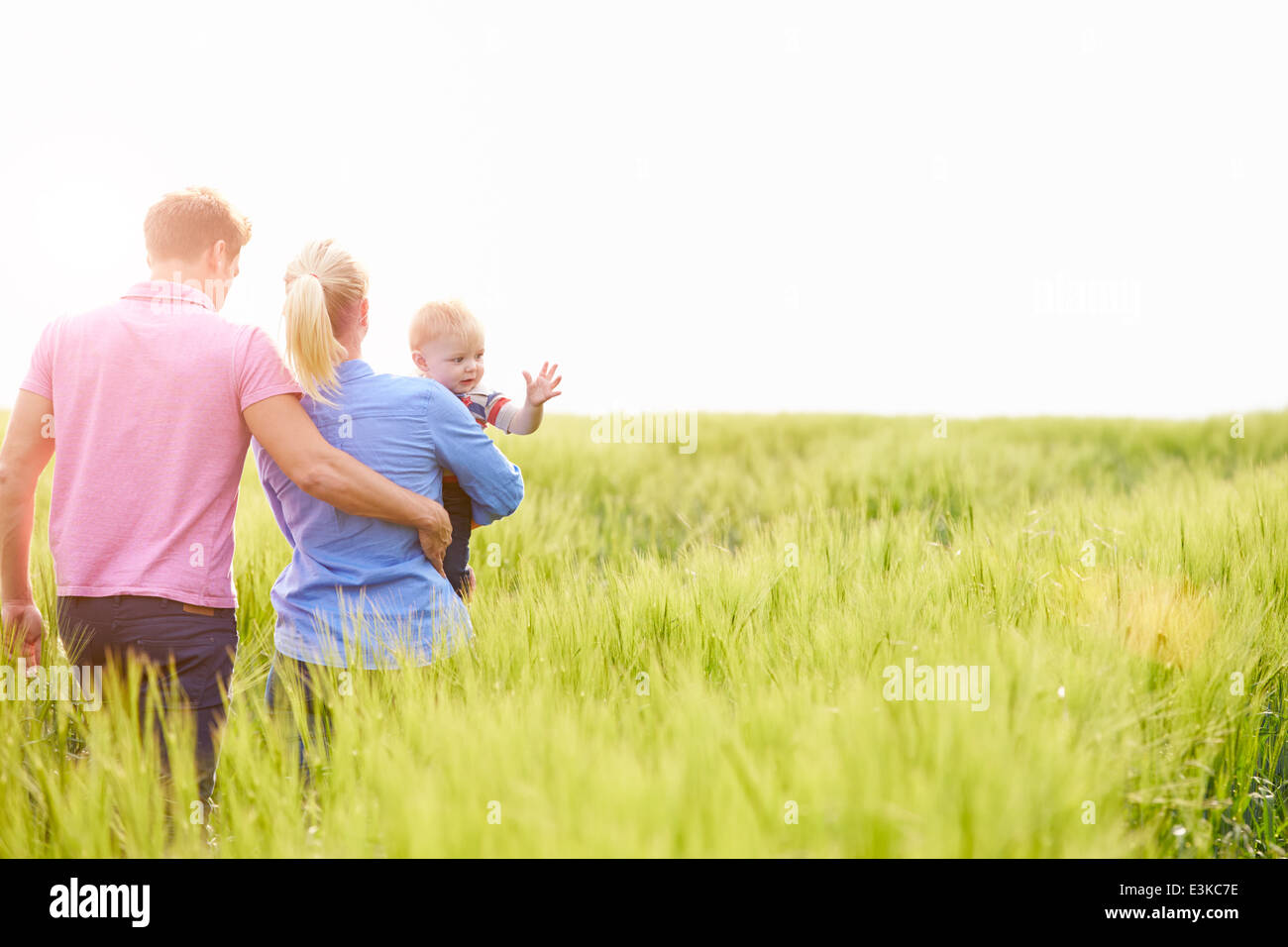 Famiglia passeggiate nel campo portando giovane figlio bambino Foto Stock