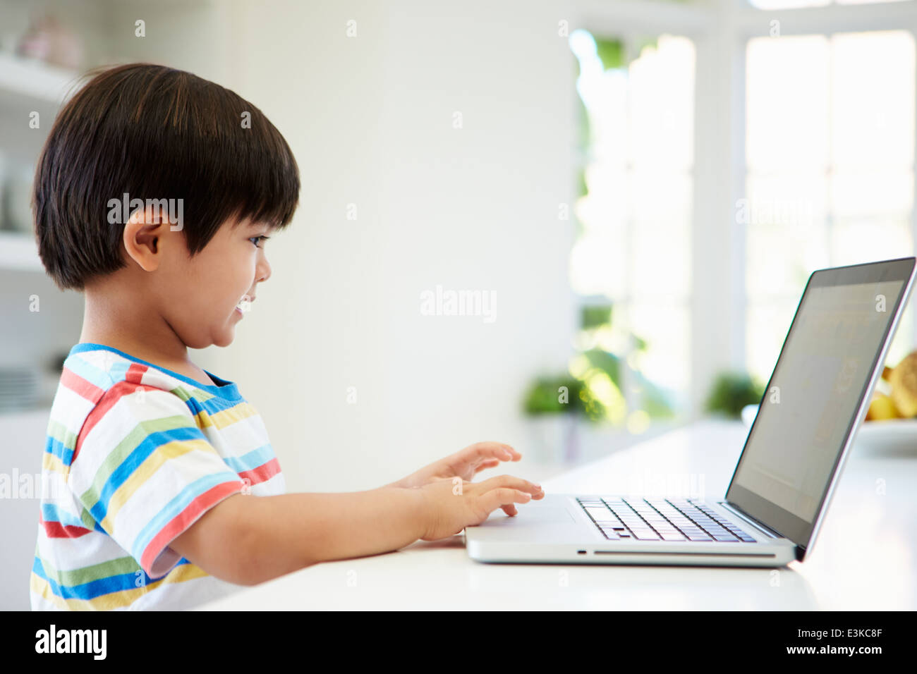 Bambino asiatico utilizzando portatile a casa Foto Stock