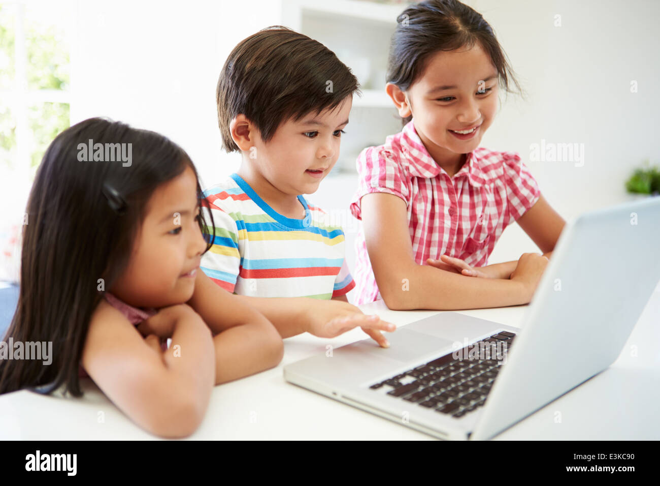 Tre bambini asiatici utilizzando portatile a casa Foto Stock