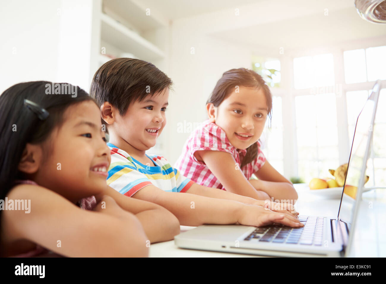 Tre bambini asiatici utilizzando portatile a casa Foto Stock