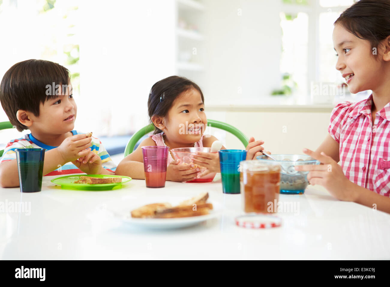 Tre bambini asiatici avente la colazione insieme in cucina Foto Stock