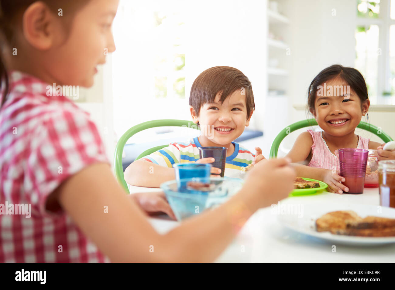 Tre bambini asiatici avente la colazione insieme in cucina Foto Stock