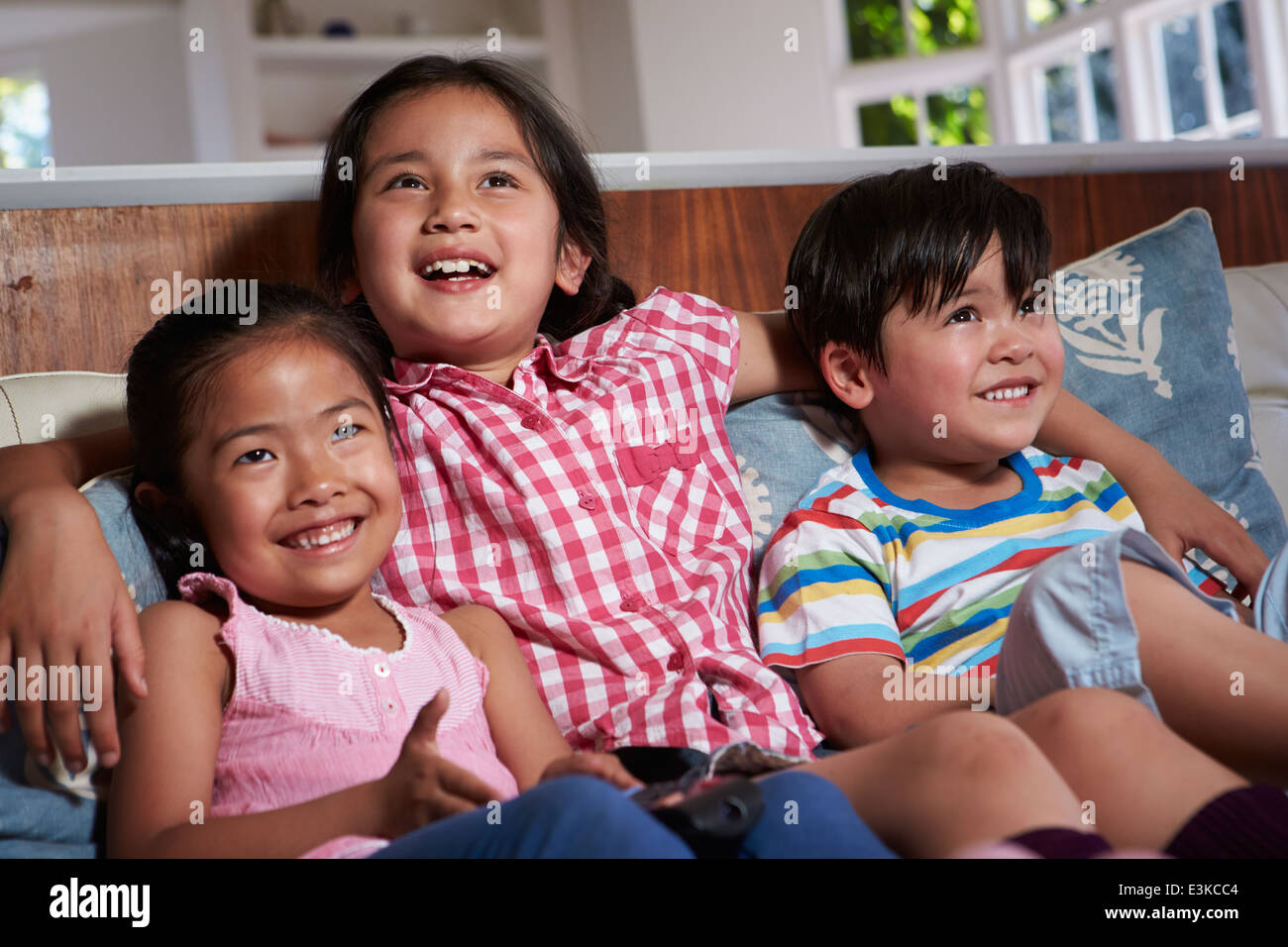 Tre asiatico i bambini seduti sul divano guardando la TV insieme Foto Stock