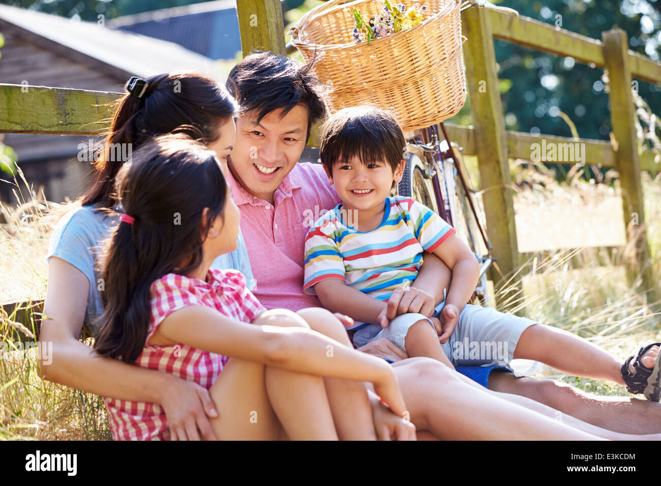 Famiglia asiatica appoggiata dal recinto con vecchio ciclo Foto Stock