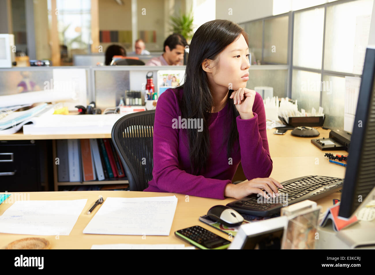 Donna asiatica lavora al computer in un ufficio moderno Foto Stock