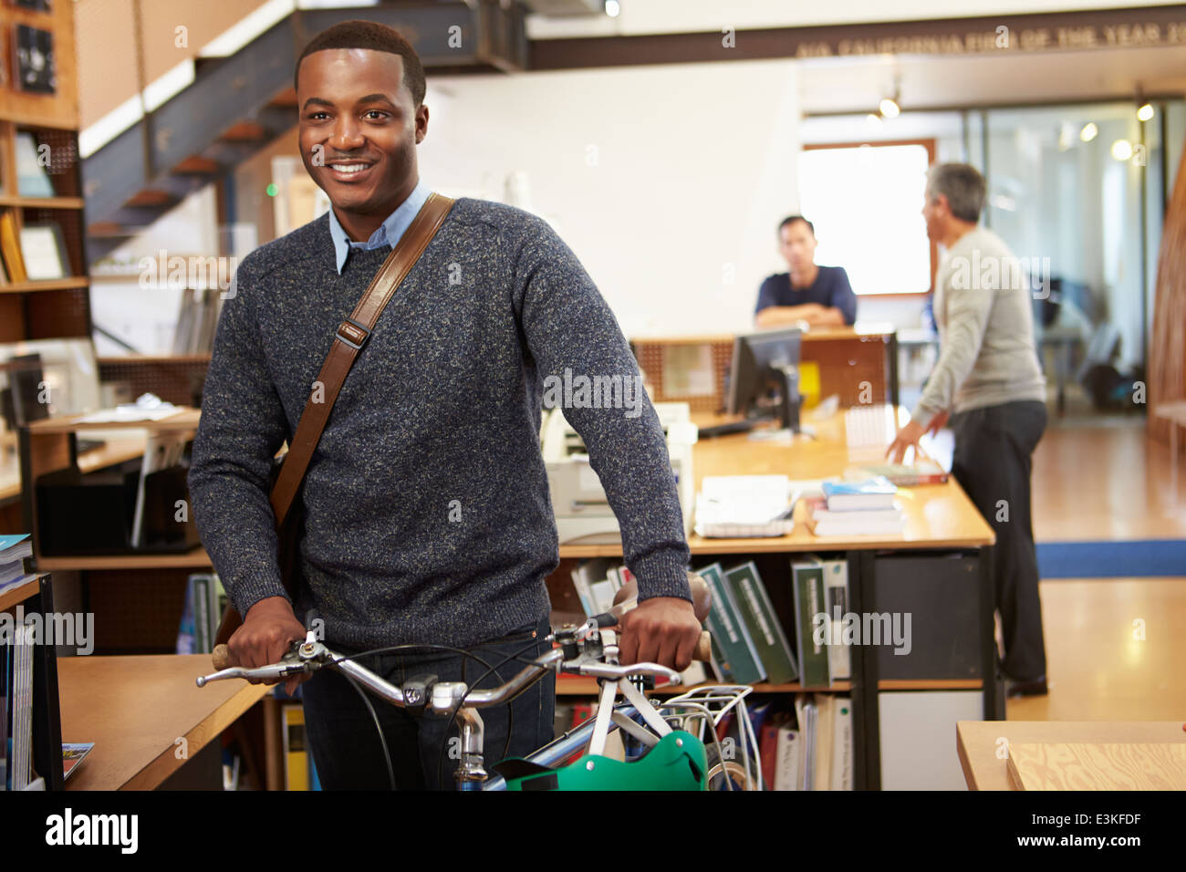 Architetto arriva a lavorare sulla moto spingendolo attraverso Office Foto Stock