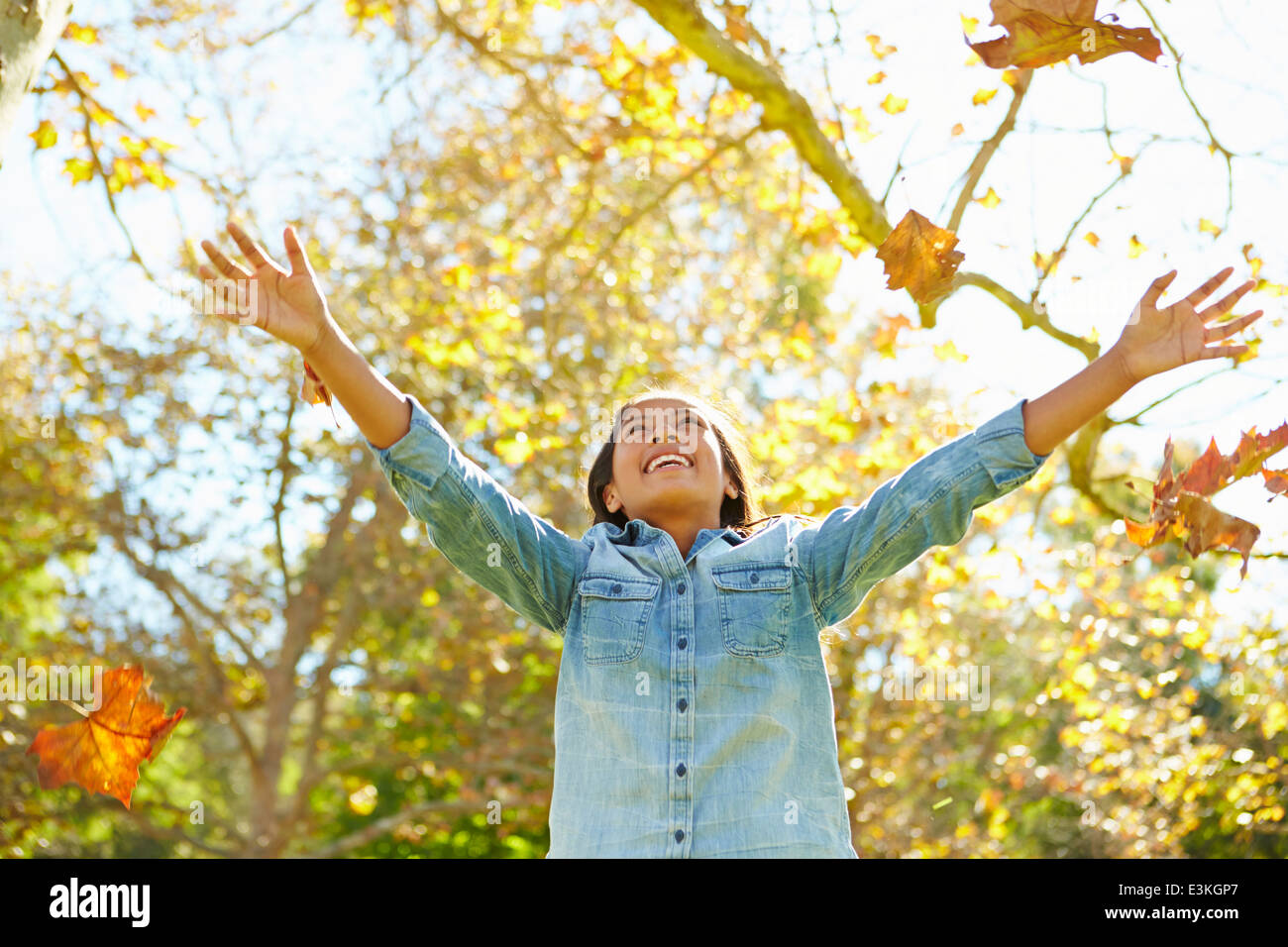 Giovane ragazza gettando le foglie di autunno in aria Foto Stock