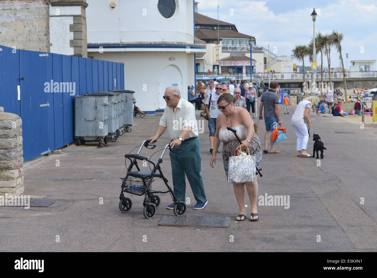 Bournemouth vecchi pensionati a piedi la spiaggia di telaio di capanne signorile di pensionamento Foto Stock