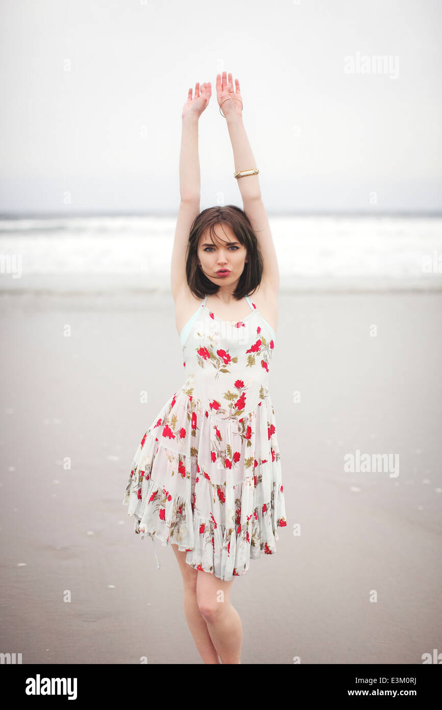 Giovane donna alzando le mani sulla spiaggia Foto Stock