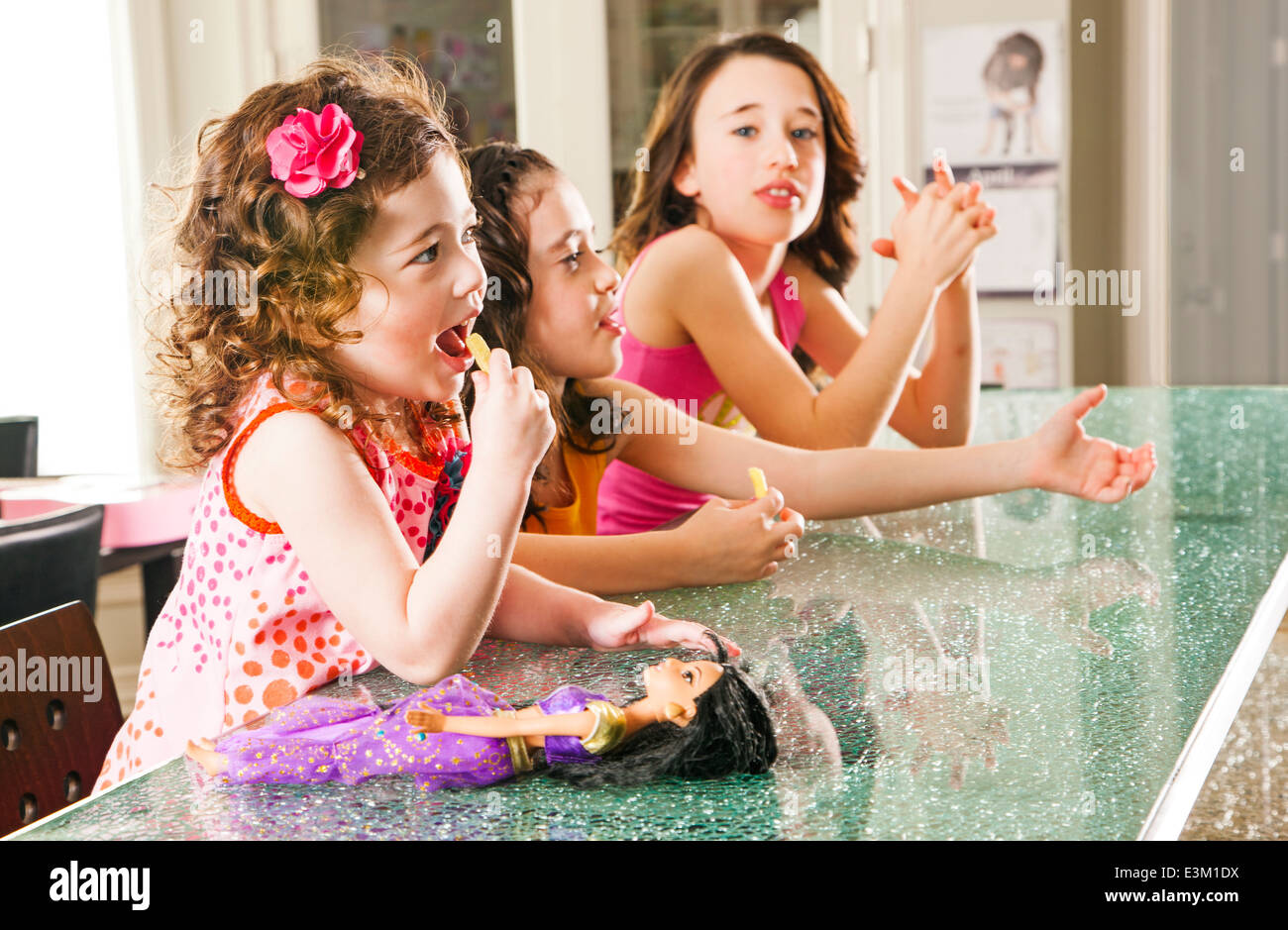 Tre ragazze (8-9, 4-5, 10-12) seduto al banco di cucina Foto Stock