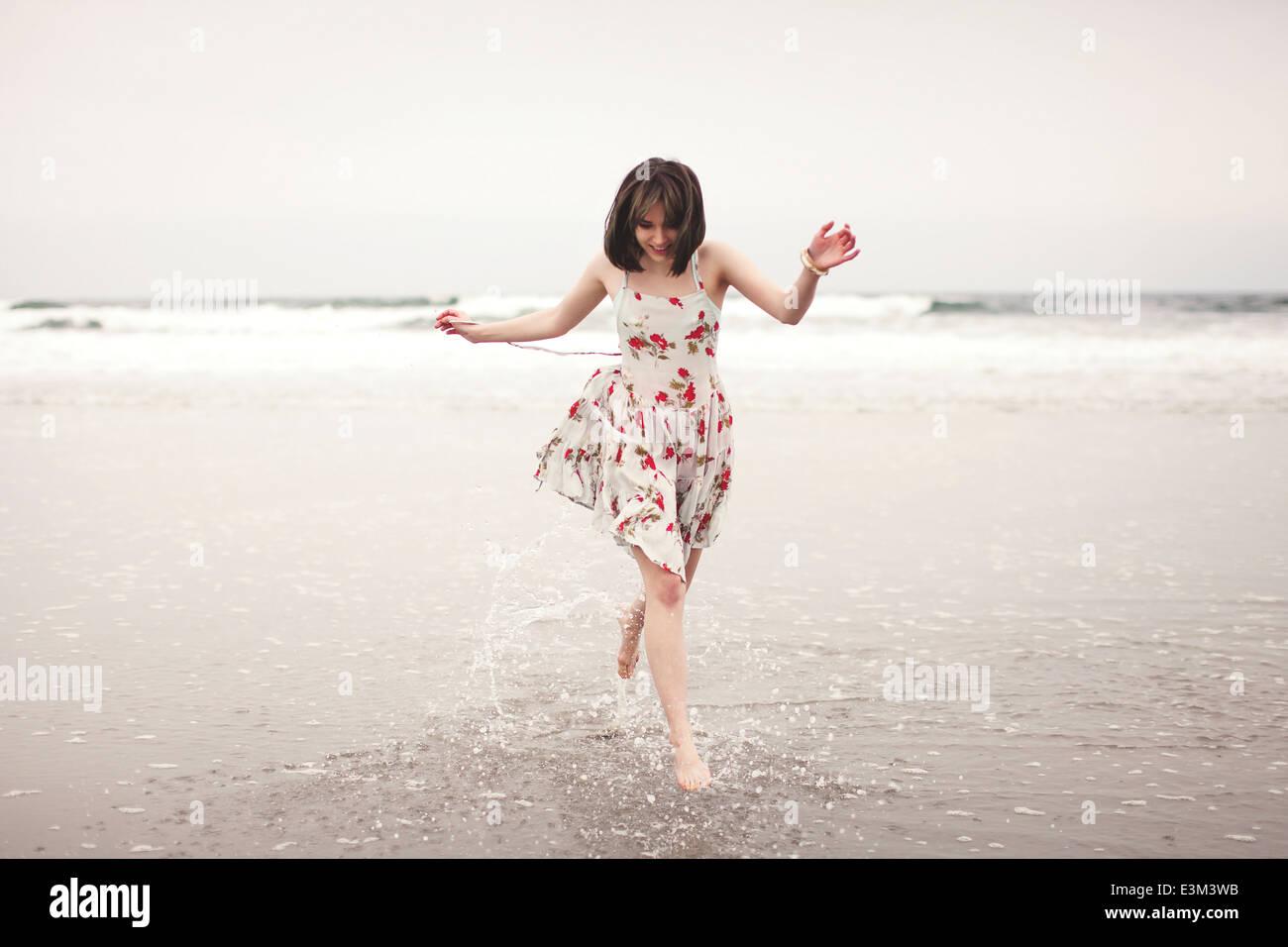 Giovane donna in esecuzione in acque poco profonde sulla spiaggia Foto Stock