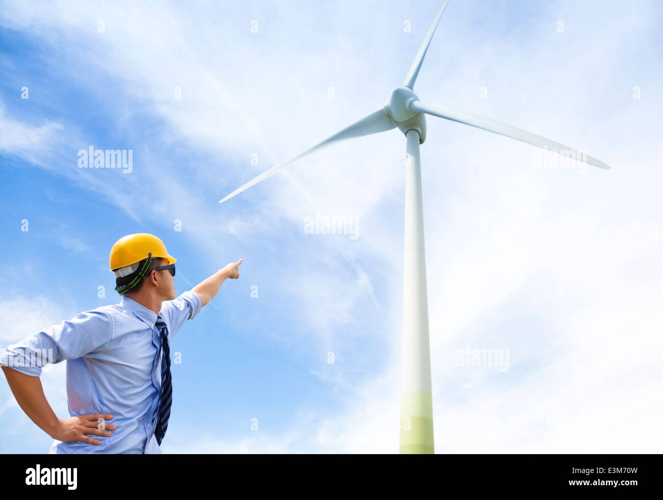 Giovane ingegnere in piedi e punto di generatore a vento Foto Stock