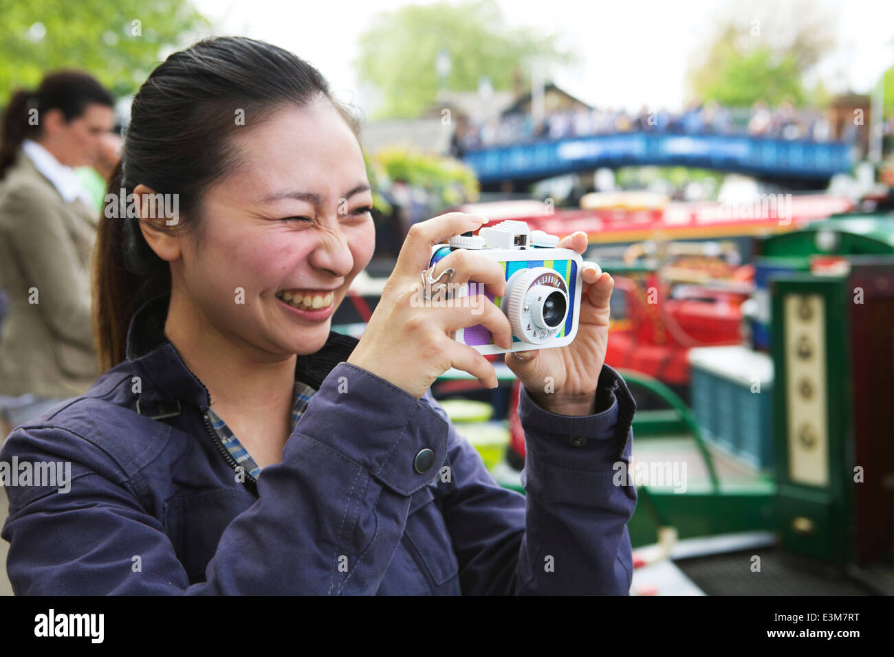 Lomography: La Sardina Saint Tropez fotocamera a pellicola. Sorridente Asian giovane adulto di sesso femminile di scattare una foto a Little Venice, Londra, Regno Unito. Foto Stock