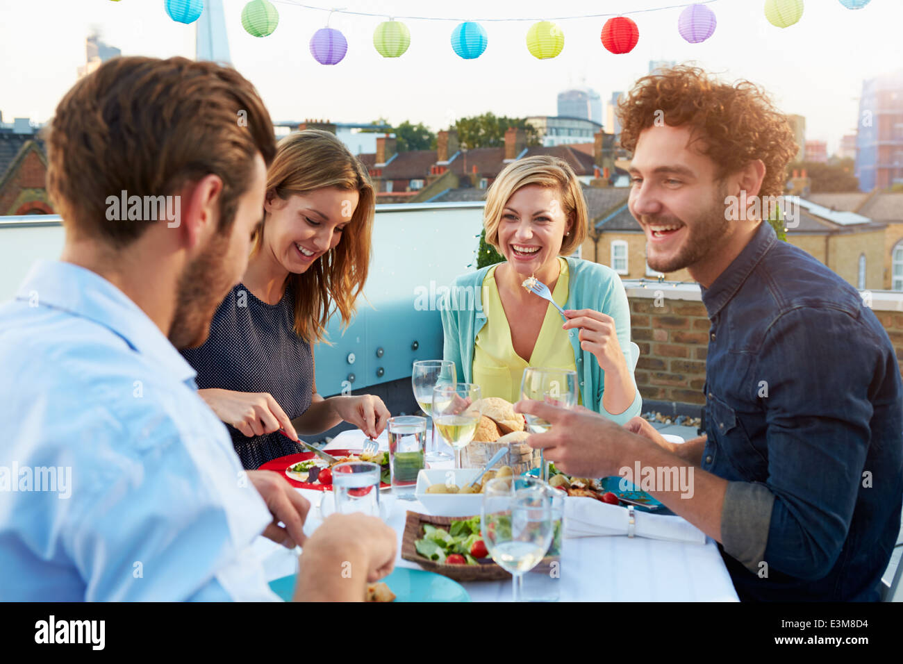 Gruppo di amici di mangiare pasti sulla terrazza sul tetto Foto Stock