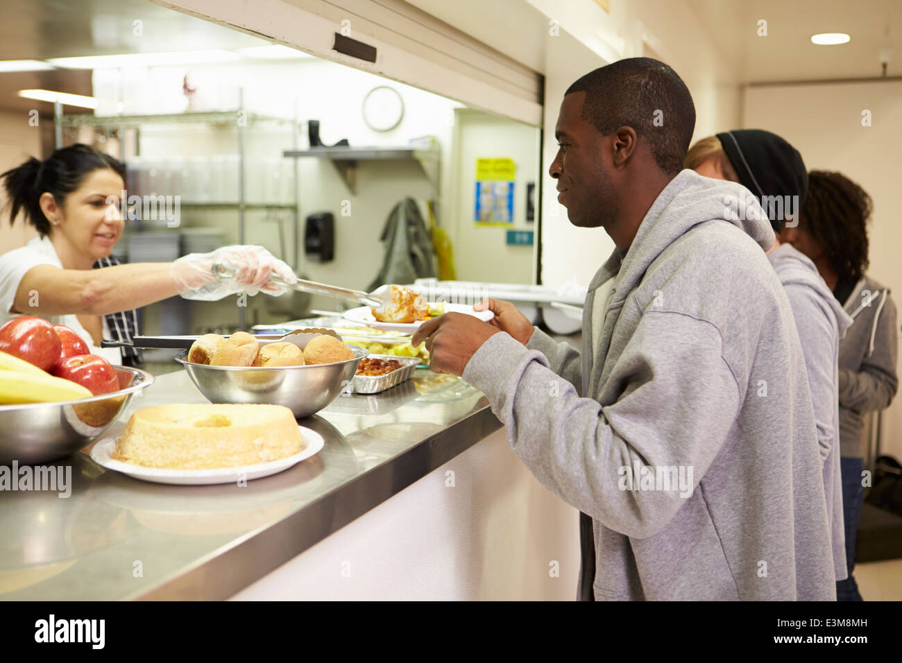 Cucina che serve cibo nel rifugio senzatetto Foto Stock
