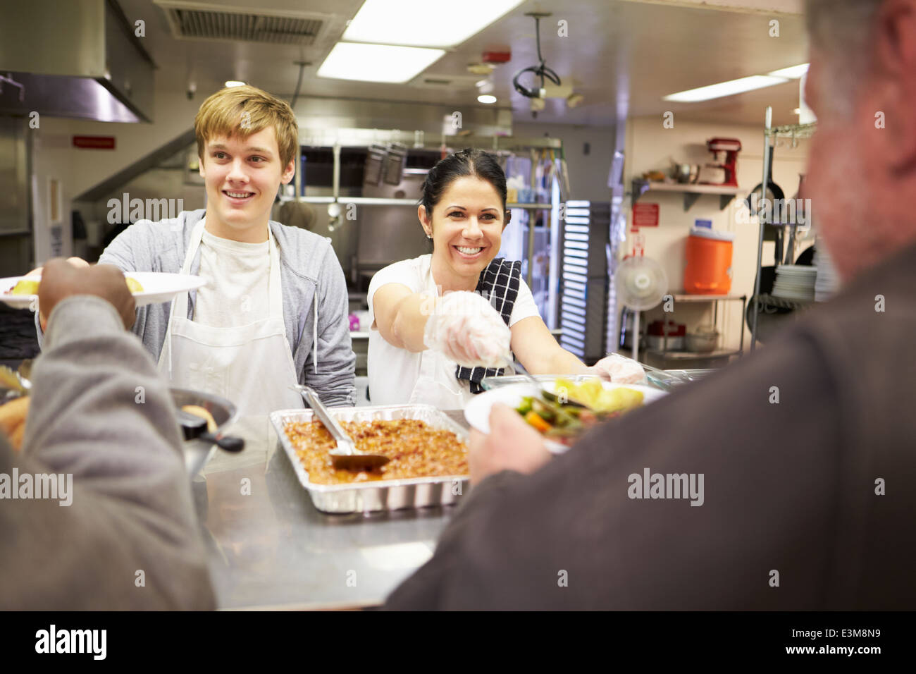 Il personale che serve cibo a ricovero per senzatetto cucina Foto Stock