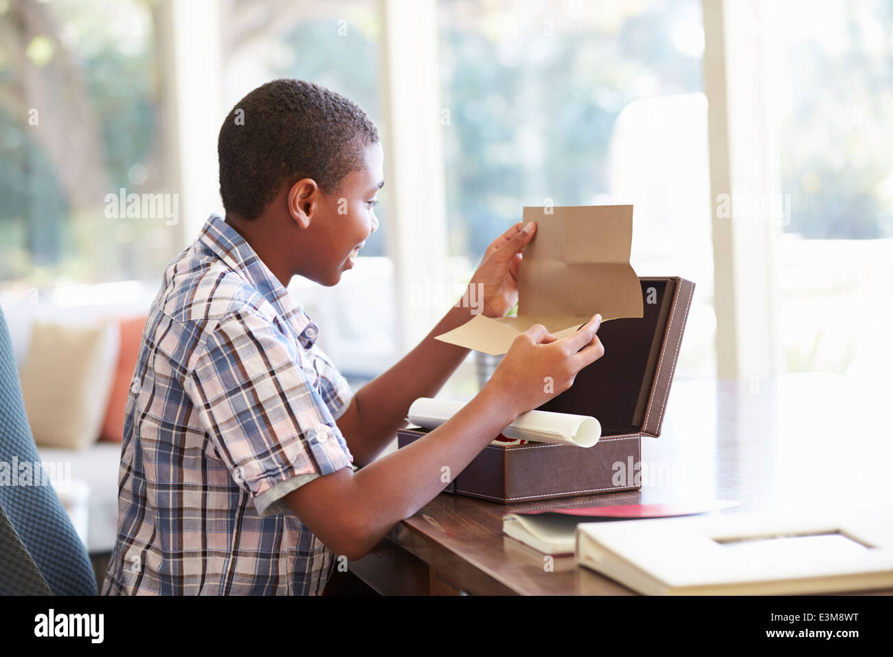 Ragazzo che guarda alla lettera nella casella di ricordo sulla scrivania Foto Stock