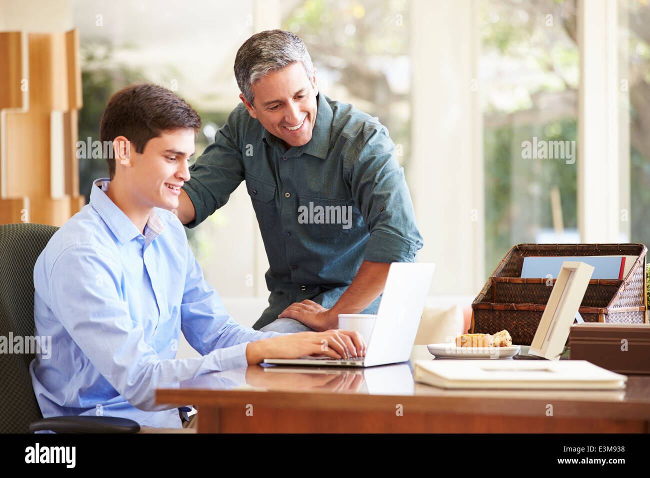 Padre e figlio adolescente Guardando insieme per Laptop Foto Stock