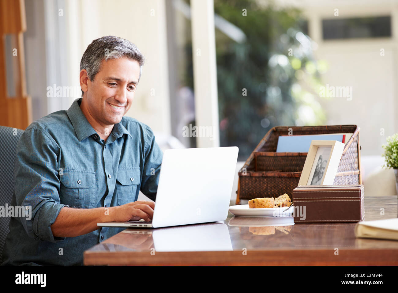 Maturo uomo ispanico utilizzando laptop sulla scrivania a casa Foto Stock