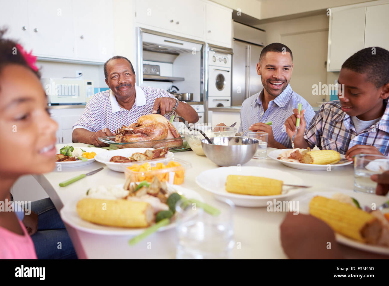 Famiglia Multi-Generation seduti a tavola a mangiare pasti Foto Stock