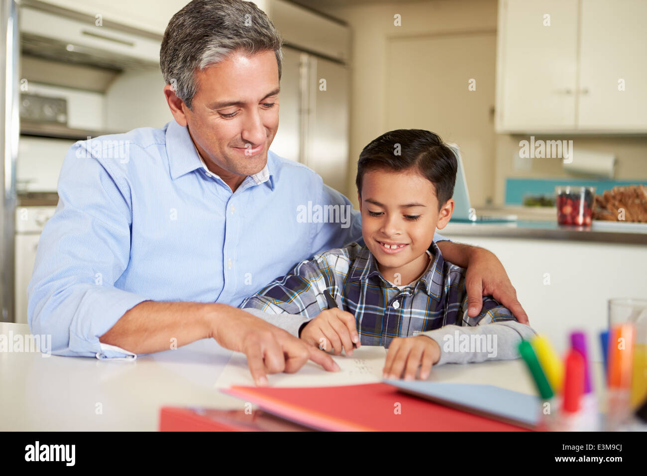 Padre ispanica aiutando figlio con i compiti a tavola Foto Stock