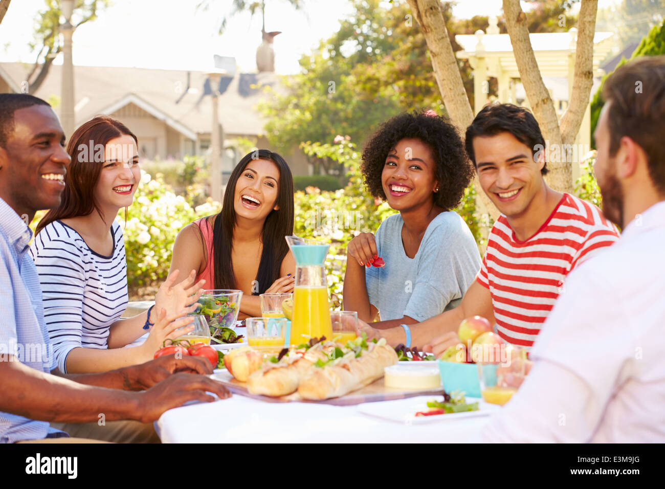 Gruppo di amici godendo di pasto al party all'aperto in cortile Foto Stock
