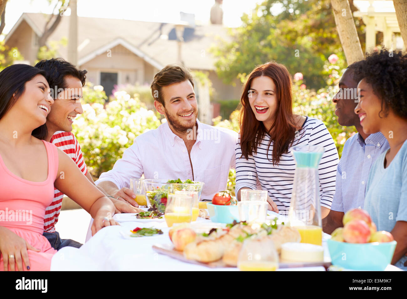 Gruppo di amici godendo di pasto al party all'aperto in cortile Foto Stock