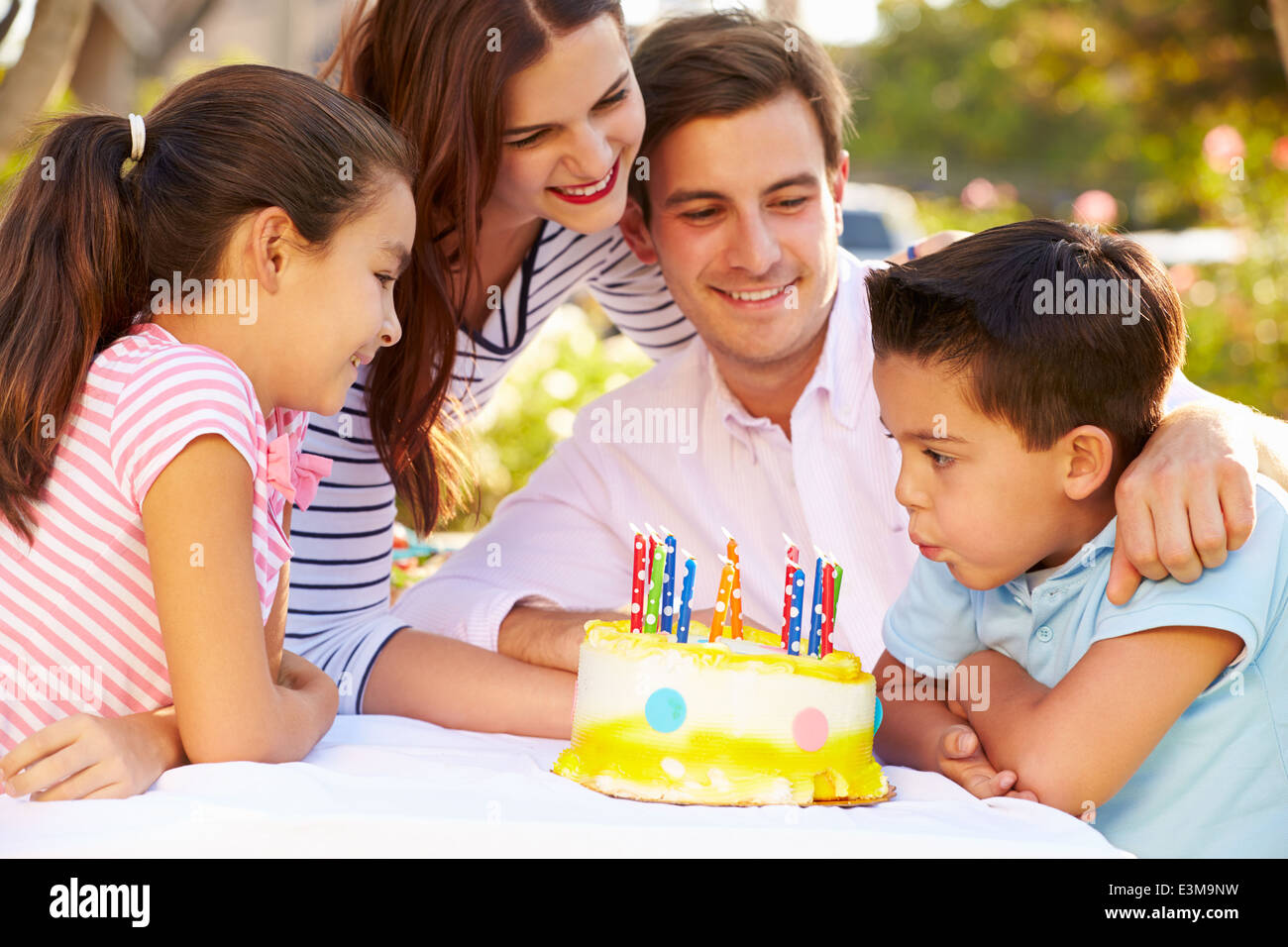 Famiglia festeggia il compleanno all'aperto con torta Foto Stock