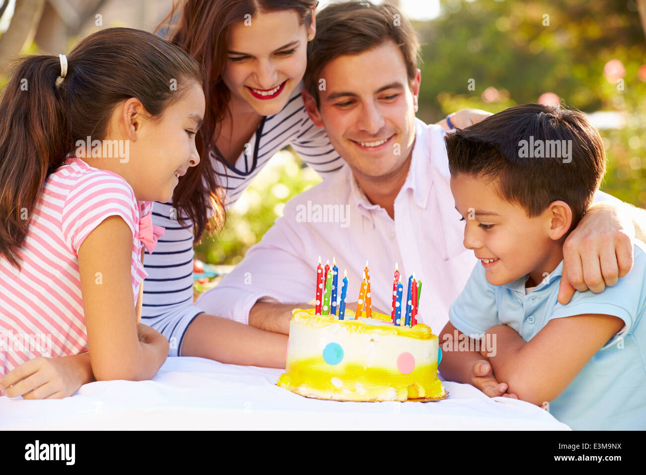 Famiglia festeggia il compleanno all'aperto con torta Foto Stock
