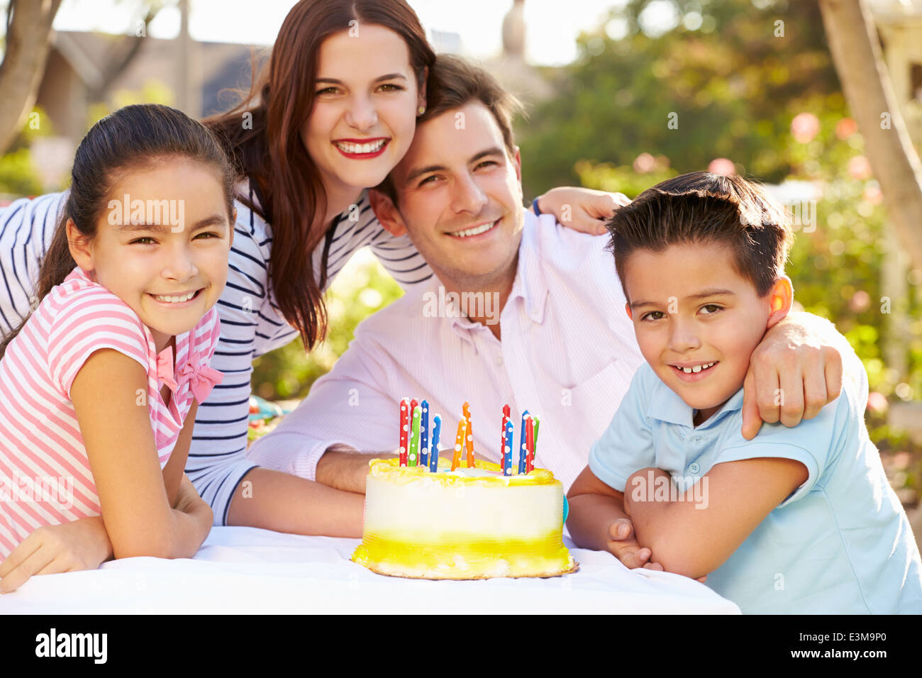 Famiglia festeggia il compleanno all'aperto con torta Foto Stock