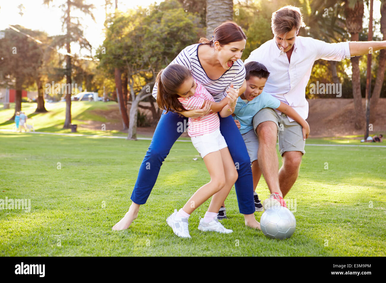 La famiglia che giocano a calcio nel parco insieme Foto Stock