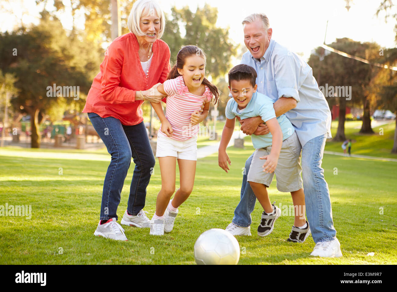 Nonni che giocano a calcio con i nipoti in posizione di parcheggio Foto Stock