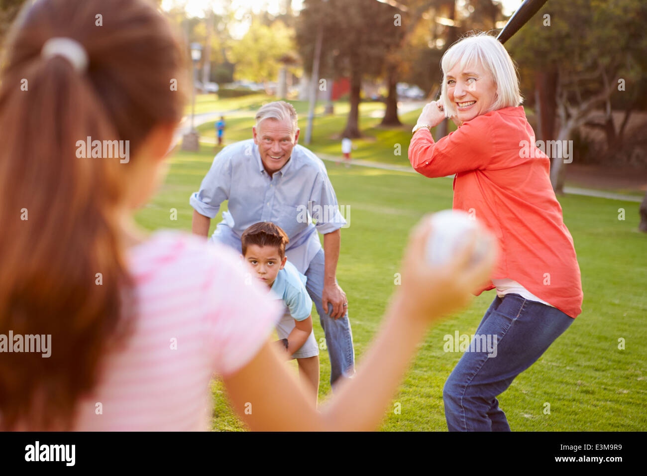 Nonni a giocare a baseball con i nipoti in posizione di parcheggio Foto Stock