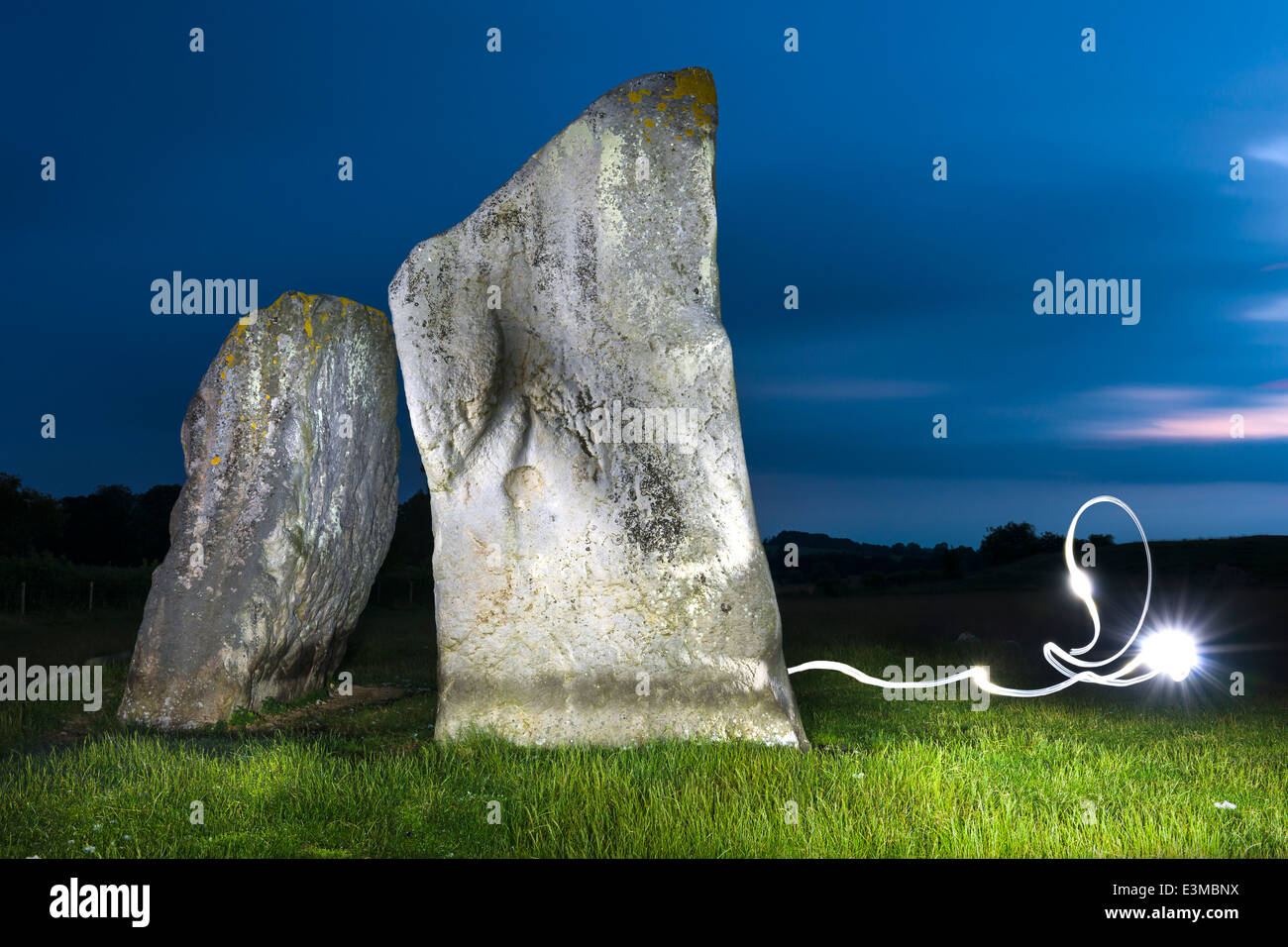 Due delle pietre Sarsen, illuminate da fiaccole, ad Avebury nel Wiltshire - Inghilterra Foto Stock