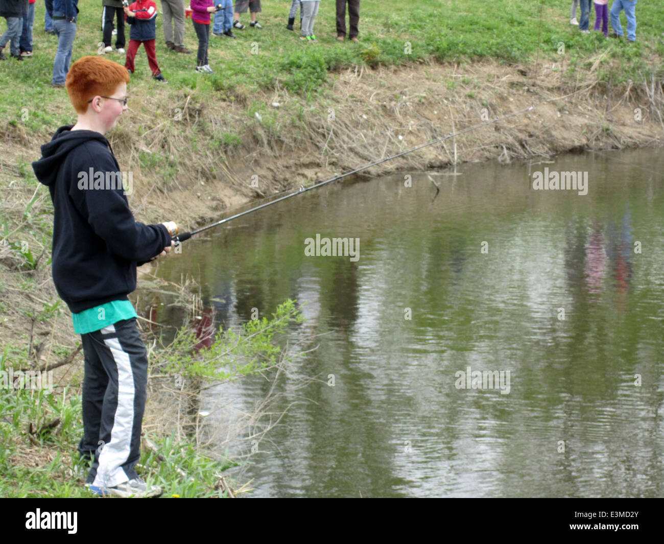 Un giovane studente ama concedersi un momento di contemplazione mentre pesca in un National Wildlife Refuge in Minnesota. L'esperienza fornisce una preziosa educazione ambientale e incoraggia i giovani a entrare in contatto con la natura. Foto Stock