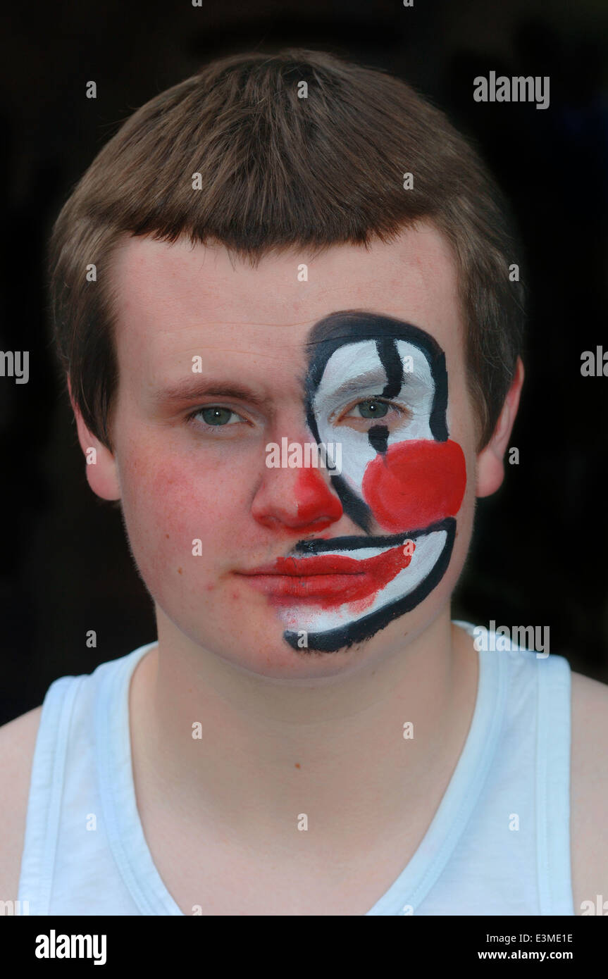 Adolescente con la metà del suo volto dipinto come un clown. Foto Stock