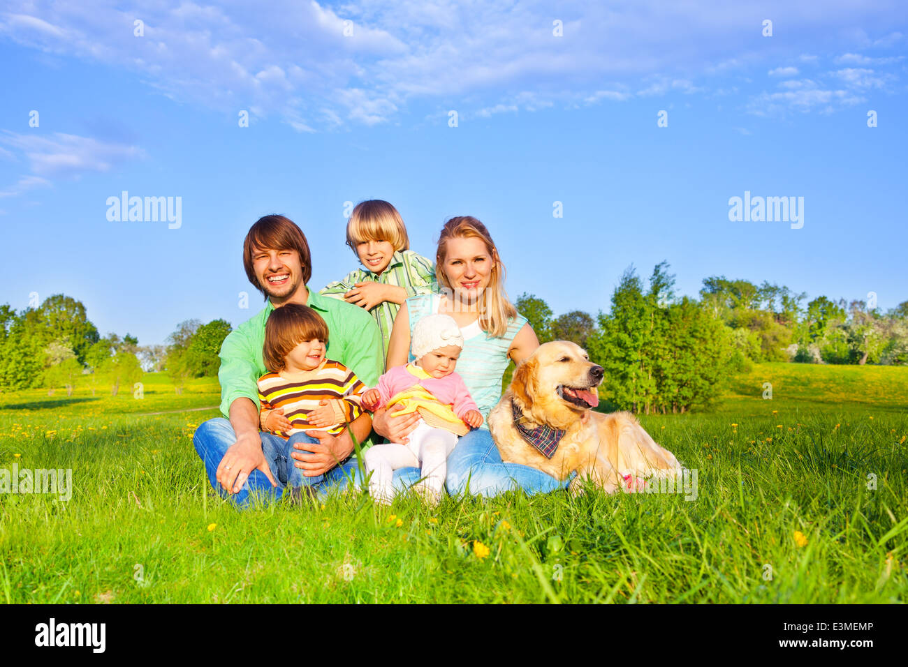 Famiglia seduta sul prato verde con il cane Foto Stock