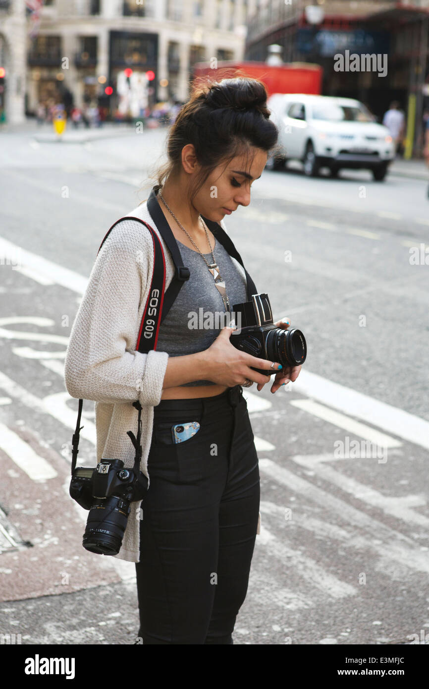 Giovane femmina attraente studente di fotografia con la Hasselblad e fotocamera digitale per scattare delle foto in Regent Street, Londra, Inghilterra. Foto Stock