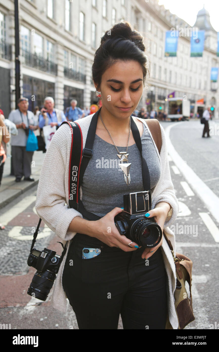 Giovane femmina attraente studente di fotografia con la Hasselblad e fotocamera digitale per scattare delle foto in Regent Street, Londra, Inghilterra. Foto Stock