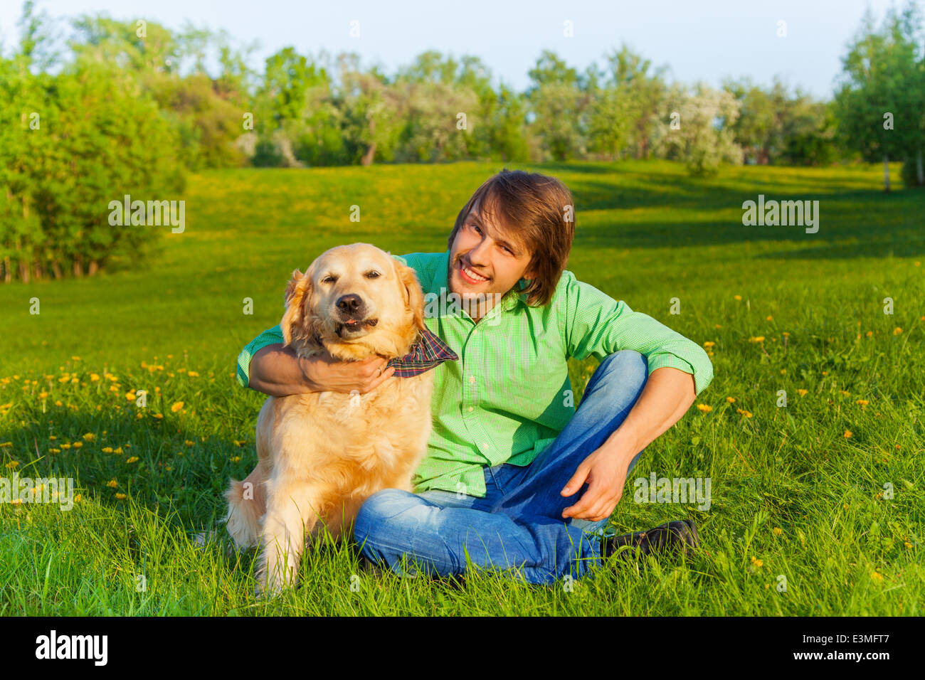 Padre sorridente con il cane seduto a terra in posizione di parcheggio Foto Stock
