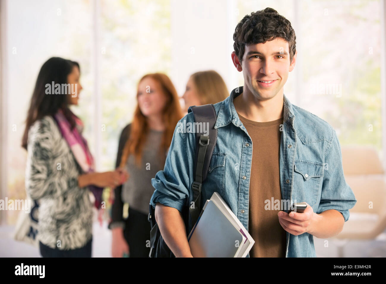 Ritratto di studente di college per la messaggistica di testo con un telefono cellulare Foto Stock