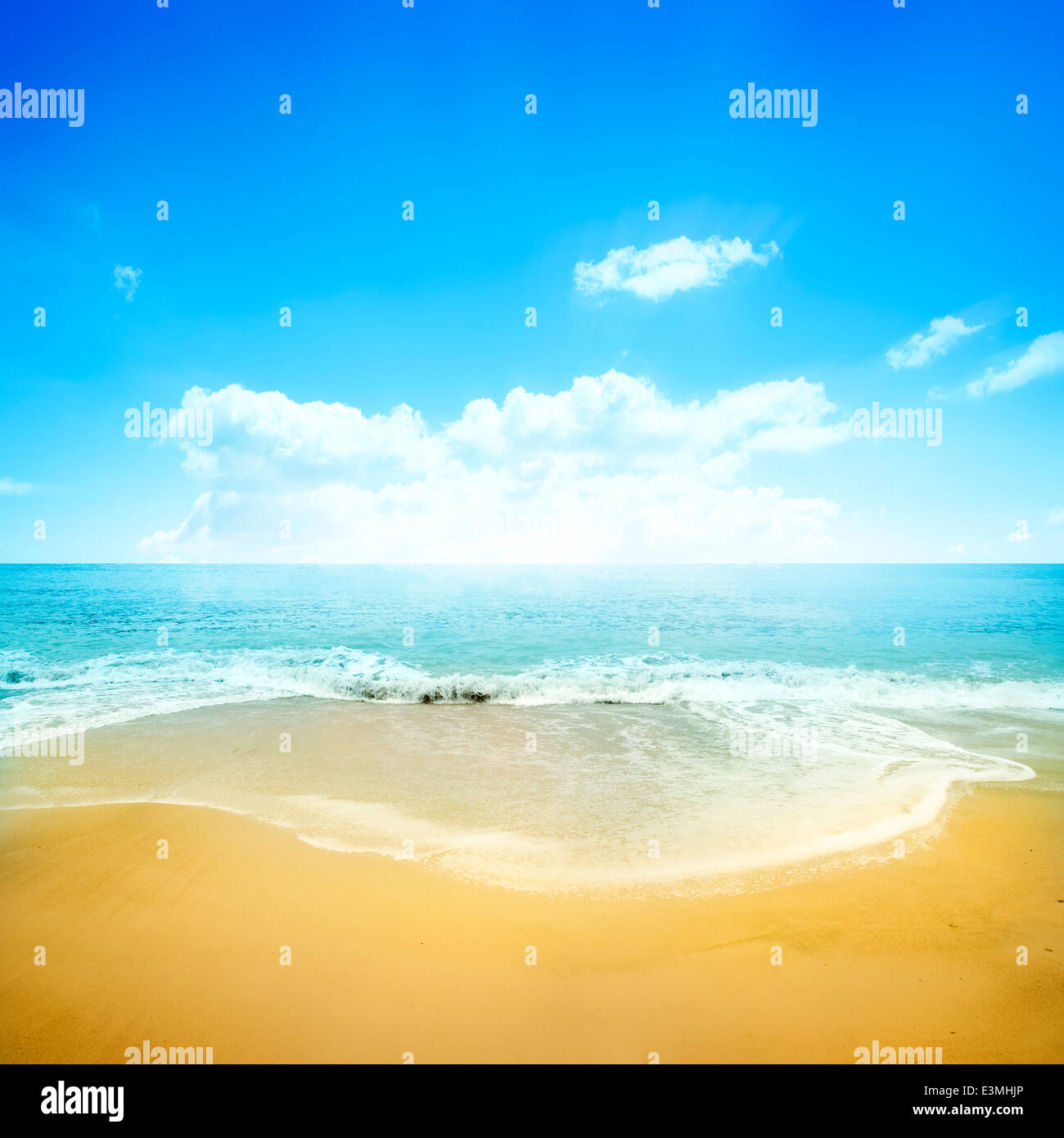 Una spiaggia di sabbia dorata e cielo blu chiaro. Vacanze estate sfondo. Foto Stock