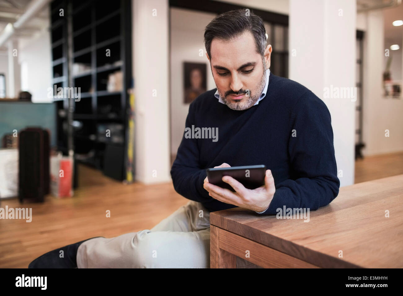 Adulto medio imprenditore utilizzando tavoletta digitale alla scrivania in ufficio Foto Stock