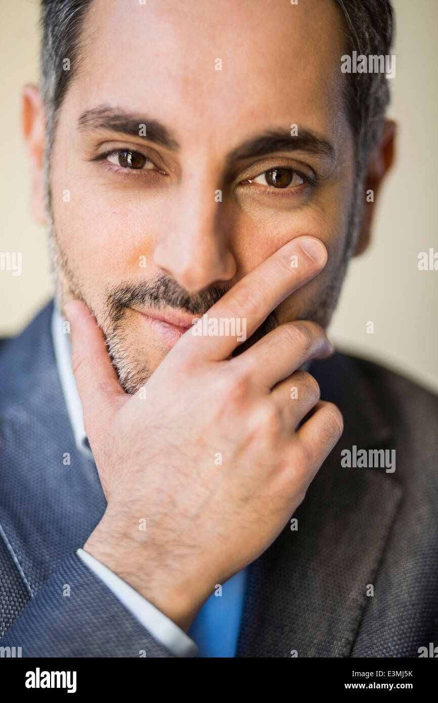 Ritratto di imprenditore fiducioso con la mano sulla faccia in ufficio Foto Stock