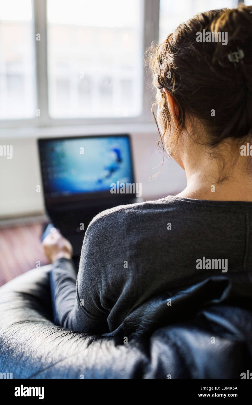 Vista posteriore della coppia imprenditrice utilizzando computer portatile mentre è seduto sul bean bag in office Foto Stock