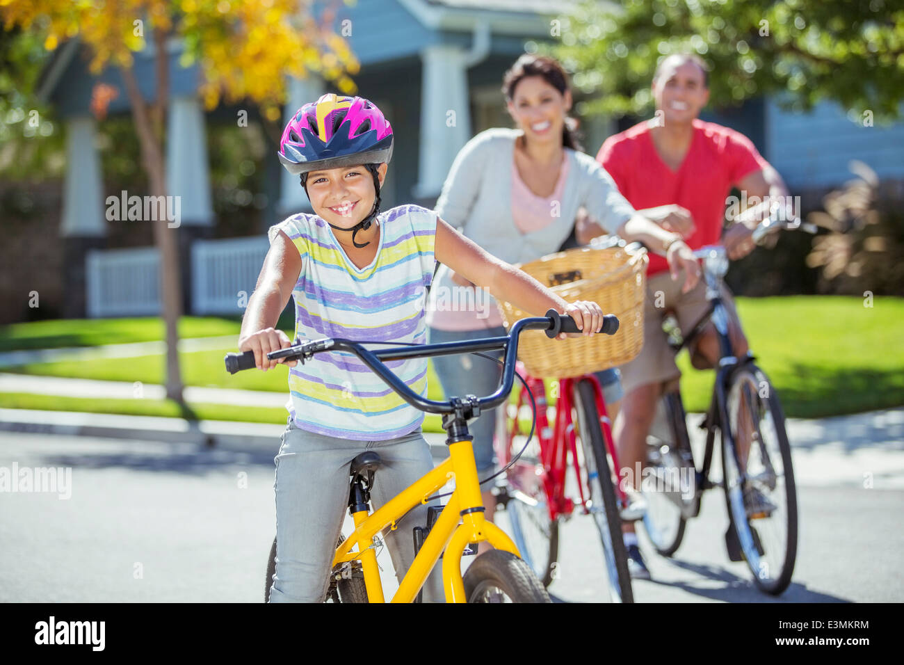 Ritratto di famiglia sorridente a cavallo di biciclette in strada Foto Stock