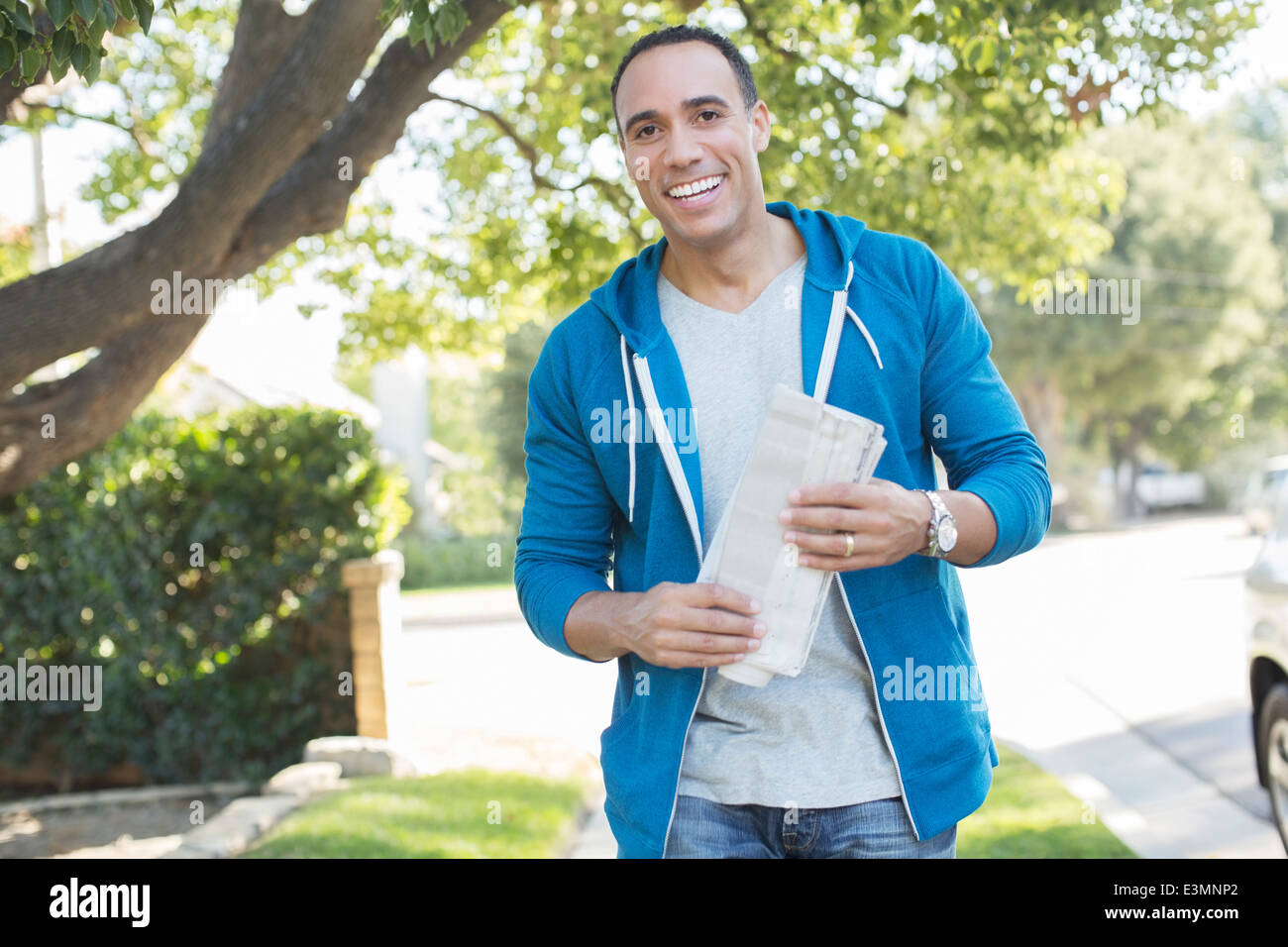 Ritratto di uomo sorridente con quotidiano all'aperto Foto Stock